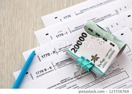 Annual Individual Income Tax Return forms with pen and indonesian rupiah bills 125556769