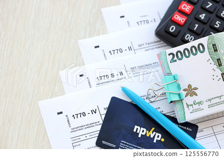 Annual Individual Income Tax Return forms with pen and indonesian rupiah bills 125556770