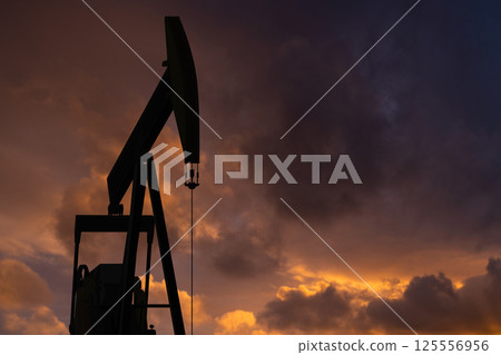 Oil rig on a background of a dramatic sky. Symbol of the collapse in the oil industry Oil rig on a background of a dramatic sky. Symbol of the collapse in the oil industry 125556956