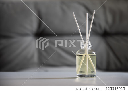 Aromatherapy reed diffuser bottle with fragrance oil and sticks on a gray blurred background. Home interior. Wellness and relaxation Aromatherapy reed diffuser bottle with fragrance oil and sticks on a gray blurred background. Home interior. Wellness and relaxation 125557025