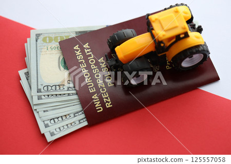 Red polish passport and yellow tractor on US money and smooth red and white flag of Poland Red polish passport and yellow tractor on US money and smooth red and white flag of Poland 125557058