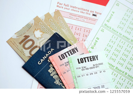 Lottery tickets lies with canadian dollars on gambling sheets with numbers for marking to play lottery Lottery tickets lies with canadian dollars on gambling sheets with numbers for marking to play lottery 125557059