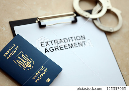Passport of Ukraine and Extradition Agreement with handcuffs on table Passport of Ukraine and Extradition Agreement with handcuffs on table 125557065