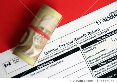 Canadian T1 General tax form Income tax and benefit return lies on table with canadian money bills Canadian T1 General tax form Income tax and benefit return lies on table with canadian money bills 125557072