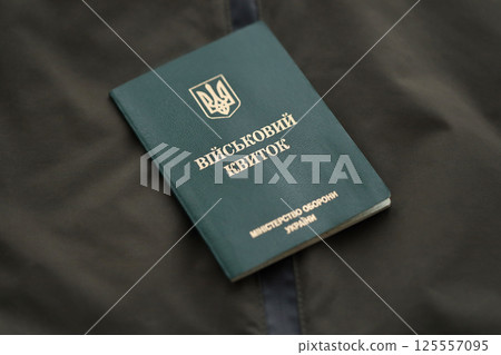 Military token or army ID ticket lies on green ukrainian military uniform 125557095
