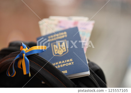 Ukrainian biometrical passport and UAH money bills on touristic backpack 125557105