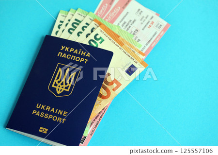 Ukrainian biometrical passport and european Euro money bills with Airlines avia tickets on blue Ukrainian biometrical passport and european Euro money bills with Airlines avia tickets on blue 125557106
