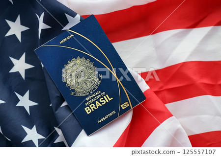 Blue Brazilian passport on United States national flag background close up Blue Brazilian passport on United States national flag background close up 125557107