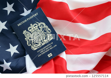 Blue British passport on United States national flag background close up 125557114