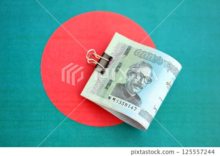 Bangladeshi taka money bills in big amount lies on Bangladesh flag close up 125557244