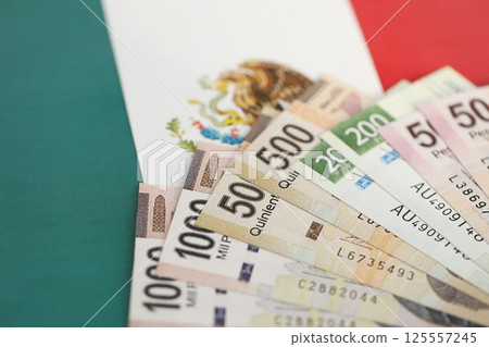 Mexican pesos money bills in big amount lies on Mexico flag close up Mexican pesos money bills in big amount lies on Mexico flag close up 125557245