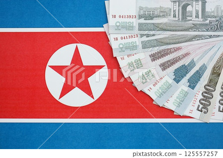 North Korean won money bills in big amount lies on People Republic of Korea flag close up 125557257