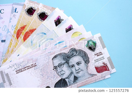 Argentine pesos money bills in big amount lies on teal color table close up 125557276