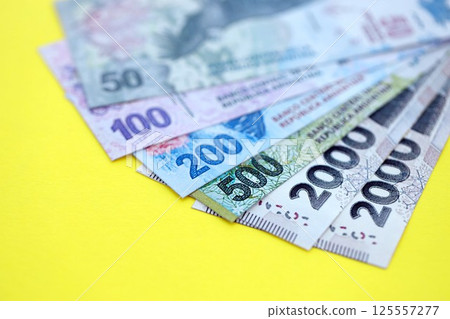 Argentine pesos money bills in big amount lies on yellow color table close up 125557277