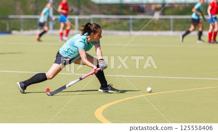 Young field hockey player hitting the ball during a match 125558406
