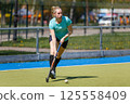 Young sportswoman leading the ball at the field hockey game 125558409