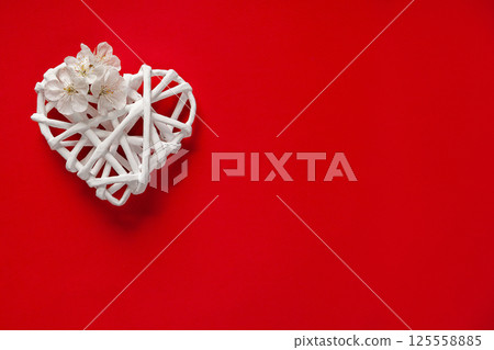 White Wicker Heart Decorated with White Flowers on Bright Red Background White Wicker Heart Decorated with White Flowers on Bright Red Background 125558885
