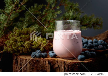 Blueberry smoothie in glass and fresh berries on a pine stump. Blueberry smoothie in glass and fresh berries on a pine stump. 125558965