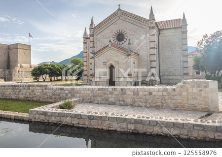 Ston, historic town in Peljesac peninsula in Croatia, Europe. Scenic view of a historic chapel near a canal with stone walls, under a bright sky, evoking tranquility and timeless charm. Ston, historic town in Peljesac peninsula in Croatia, Europe. Scenic view of a historic chapel near a canal with stone walls, under a bright sky, evoking tranquility and timeless charm. 125558976