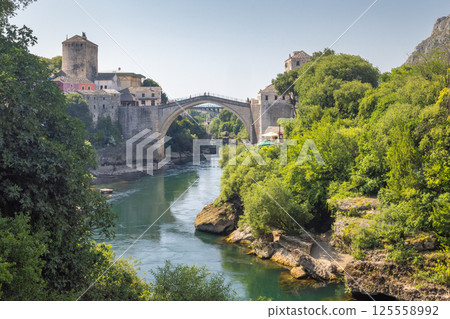 The Stari Most bridge, old bridge on Neretva river in Mostar town, Bosnia and Herzegovina, Europe. Picturesque stone bridge elegantly arches over the tranquil river. The Stari Most bridge, old bridge on Neretva river in Mostar town, Bosnia and Herzegovina, Europe. Picturesque stone bridge elegantly arches over the tranquil river. 125558992