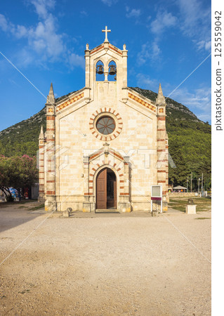 Ston, historic town in Peljesac peninsula in Croatia, Europe. Exterior facade of an old church featuring a cross on top of the building with bell towers in a European landscape. 125559042
