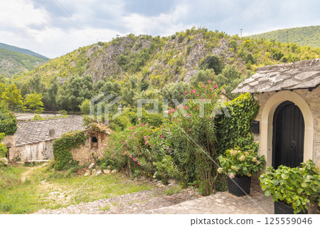 Old stone house in Blagaj village in Bosnia and Herzegovina, Europe. Stone buildings nestled in nature, with a rocky hillside backdrop. The scene is peaceful, blending architecture with environment. 125559046