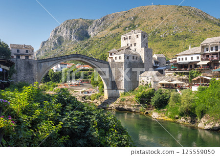 The Stari Most bridge, old bridge on Neretva river in Mostar town, Bosnia and Herzegovina, Europe. Picturesque stone bridge crossing a river with historic buildings in the background. The Stari Most bridge, old bridge on Neretva river in Mostar town, Bosnia and Herzegovina, Europe. Picturesque stone bridge crossing a river with historic buildings in the background. 125559050