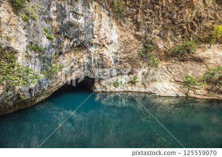 Buna river near the Blagaj Tekke monastery, Bosnia and Herzegovina, Europe. Cave opening at riverbank, with turquoise waters reflecting rock formations and vegetation in serene outdoor scenery. 125559070