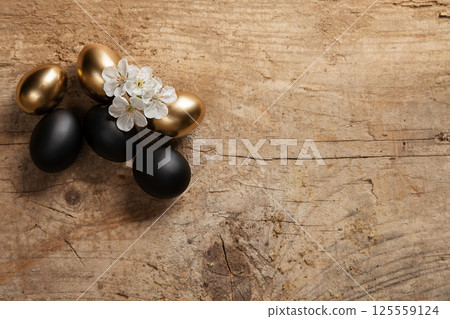 Golden and Black Eggs with White Blossoms on Rustic Wood Surface 125559124