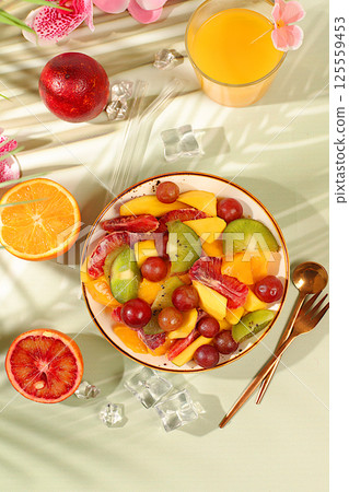 Healthy breakfast with ingredients, kitchen background. Fruit salad with kiwi, mango, grapes, nuts, citrus fruits with chia seeds for weight loss and a glass of orange juice. Natural nutrition and 125559453