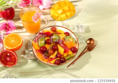 Healthy breakfast with ingredients, kitchen background. Fruit salad with kiwi, mango, grapes, nuts, citrus fruits with chia seeds for weight loss and a glass of orange juice. Natural nutrition and Healthy breakfast with ingredients, kitchen background. Fruit salad with kiwi, mango, grapes, nuts, citrus fruits with chia seeds for weight loss and a glass of orange juice. Natural nutrition and 125559458