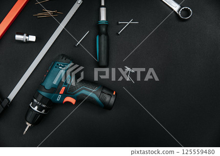 Hand tools set on dark board. Cordless drill, screwdriver, wrench, cutter. Flat lay, top view 125559480
