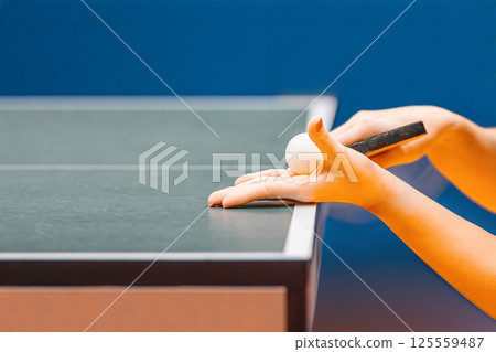 Table tennis serve, close up view of woman playing ping pong. Table tennis ball and bat in hands Table tennis serve, close up view of woman playing ping pong. Table tennis ball and bat in hands 125559487