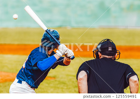 Baseball action, baseball player with bat waiting for ball with umpire, rear view. Team sports 125559491