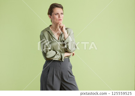 Thoughtful woman in green, hand on chin Thoughtful woman in green, hand on chin 125559525