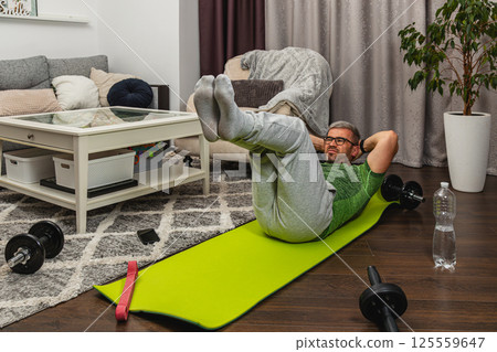 Man exercising at home on a green workout mat 125559647