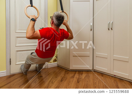 Man doing gymnastic rings workout at home 125559688