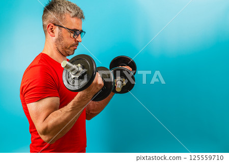 Man lifting dumbbells for strength training in gym Man lifting dumbbells for strength training in gym 125559710