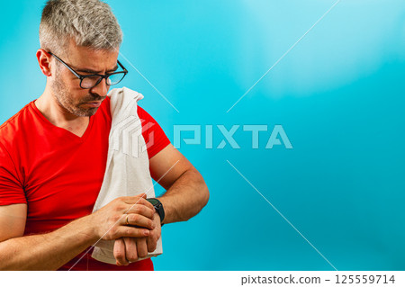 Man checking watch while adjusting towel on shoulder 125559714
