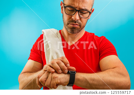 Man checking watch during workout session at gym Man checking watch during workout session at gym 125559717