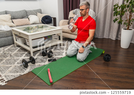Man exercising at home with weights and water bottle 125559719