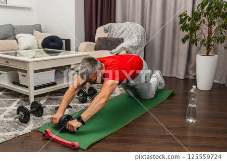 Man training with ab roller in living room Man training with ab roller in living room 125559724