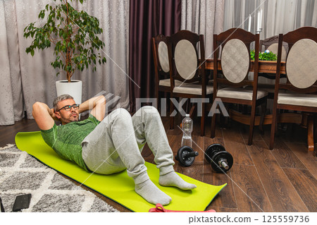 Man exercising at home with fitness equipment 125559736