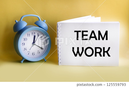 The word "TEAMWORK" is written on a notepad and a yellow background, and the clock is nearby. The word "TEAMWORK" is written on a notepad and a yellow background, and the clock is nearby. 125559793