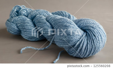 Pastel blue yarn gracefully coiling diagonally, revealing delicate texture and serene color against minimalist neutral background with elegant, soft styling 125560208