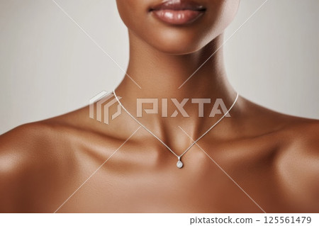 Elegant model showcases stylish silver necklace against minimalist backdrop with charm 125561479