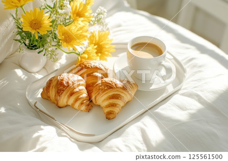 Delightful breakfast tray on a bed featuring croissants coffee and fresh flowers Delightful breakfast tray on a bed featuring croissants coffee and fresh flowers 125561500