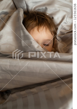Top view of cute caucasian toddler lying in bed. Top view of cute caucasian toddler lying in bed. 125561636