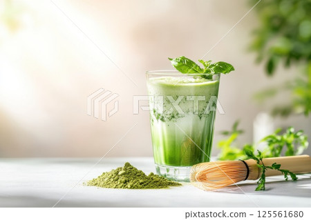 Green matcha latte in a glass served with a bamboo whisk and matcha powder 125561680