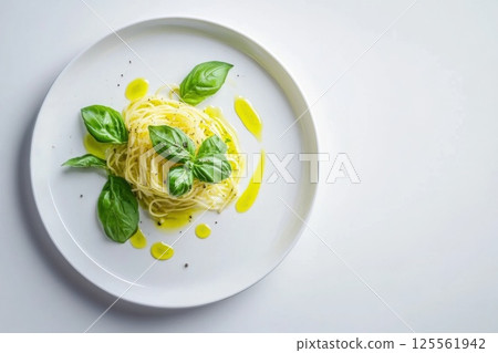 Delicate pasta dish with olive oil and fresh basil on a bright white plate 125561942